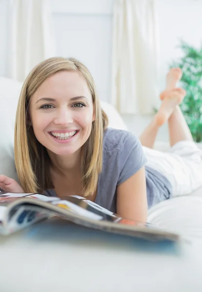 Casual woman with magazine lying on couch — Stock Photo, Image