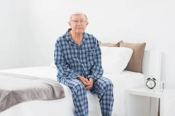 Aged man sitting on his bed — Stock Photo, Image