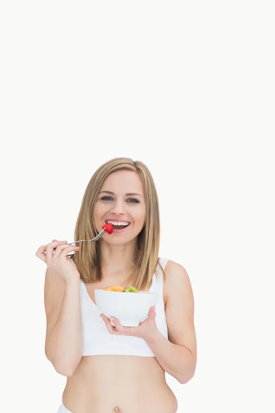 Portrait of happy woman eating from a bowl of fruits — Stock Photo, Image