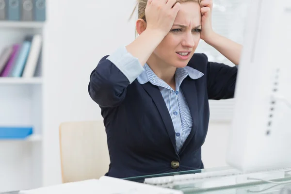 Frustrated business woman in front of computer at office desk — Stock Photo, Image