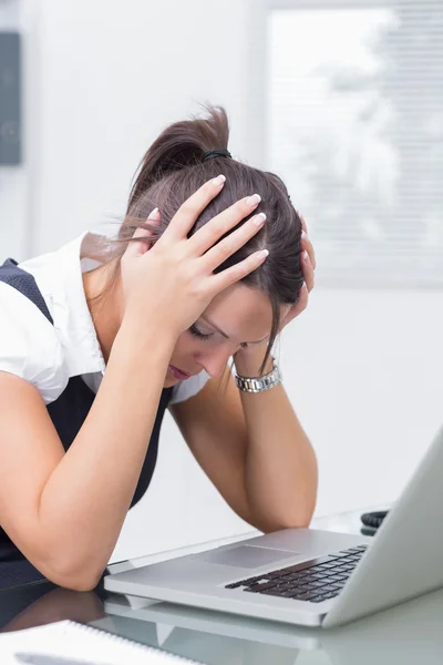 Разочарованная деловая женщина с головой в руках перед ноутбуком — стоковое фото