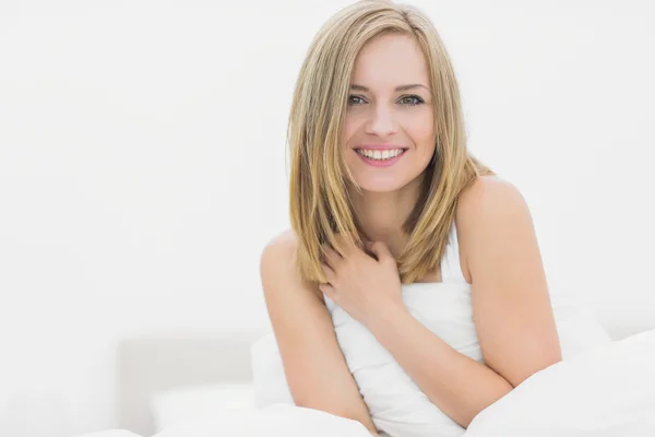 Portrait of smiling woman sitting in bed — Stock Photo, Image