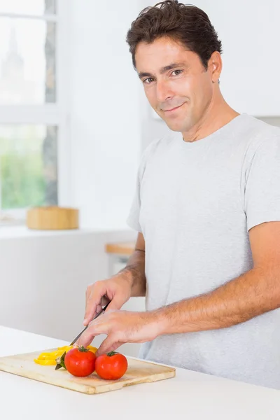 Homem sorridente cortando pimentas — Fotografia de Stock