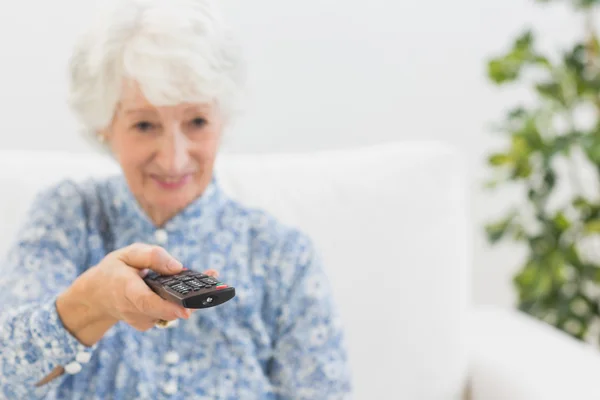 Oudere lachende vrouw met behulp van de afstandsbediening — Stockfoto