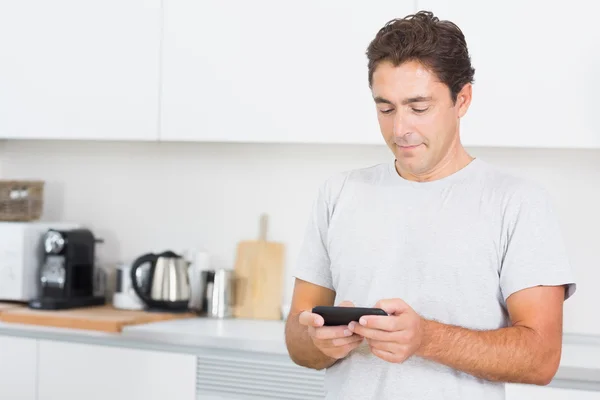 Homem mensagens de texto na cozinha — Fotografia de Stock