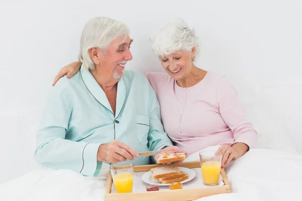 Lachende paar ontbijten in bed — Stockfoto