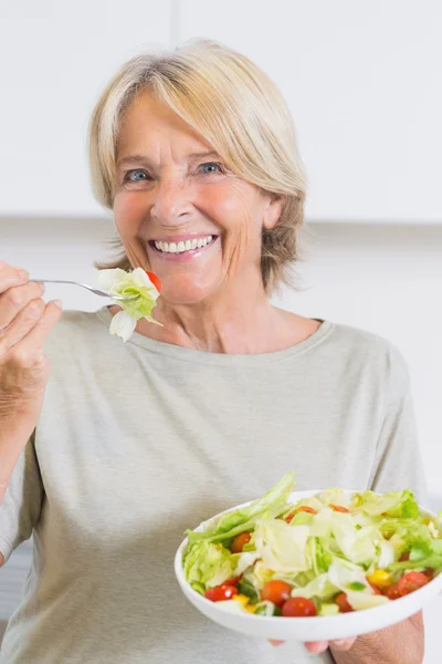 Χαμογελώντας ώριμη γυναίκα τρώει σαλάτα — Φωτογραφία Αρχείου