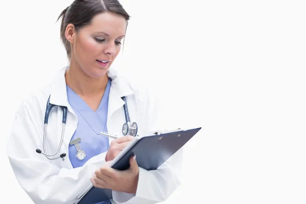 Female doctor writing on clipboard — Stock Photo, Image