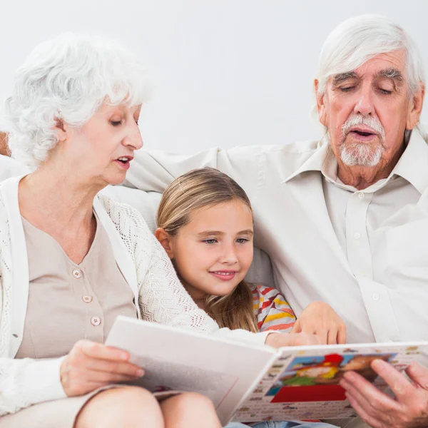 Kleines Mädchen liest mit Großeltern — Stockfoto