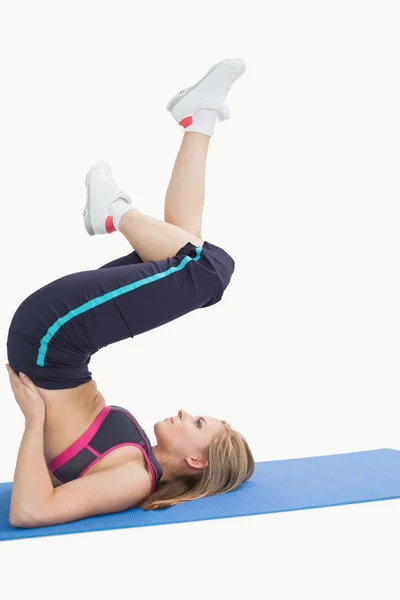 Vista lateral de la mujer en la posición del ciclo del soporte del hombro en la esterilla de yoga —  Fotos de Stock