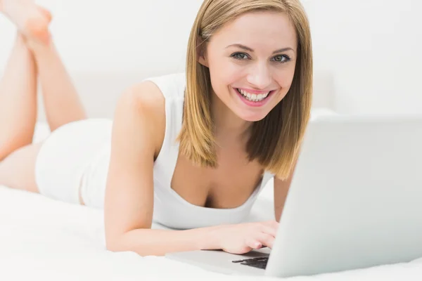 Portrét krásné šťastné ženy používat přenosný počítač v posteli — Stock fotografie