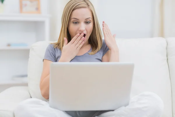 Surprised casual woman using laptop at home — Stock Photo, Image
