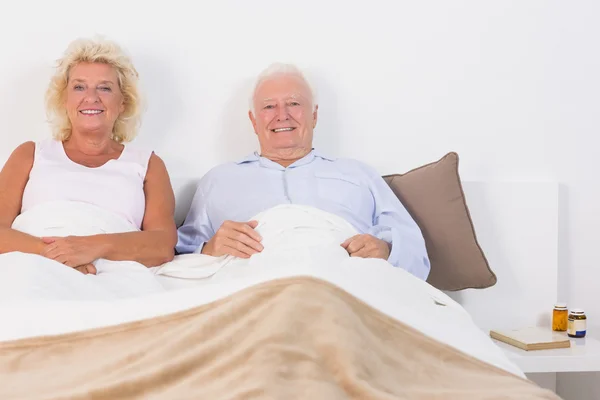 Старая пара лежит на кровати — стоковое фото