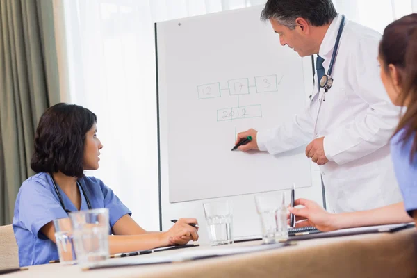 Doctor writing on presentation board — Stock Photo, Image