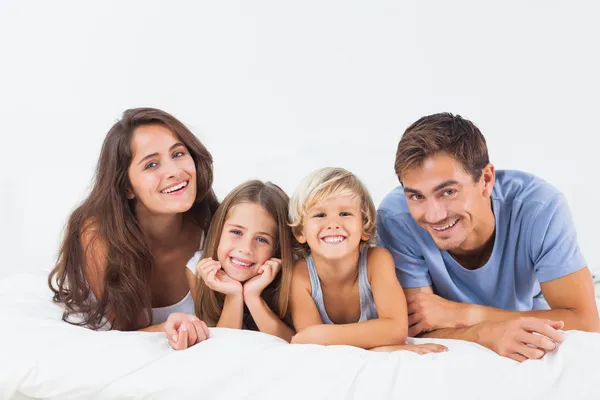 Счастливая семья лежит на кровати — стоковое фото