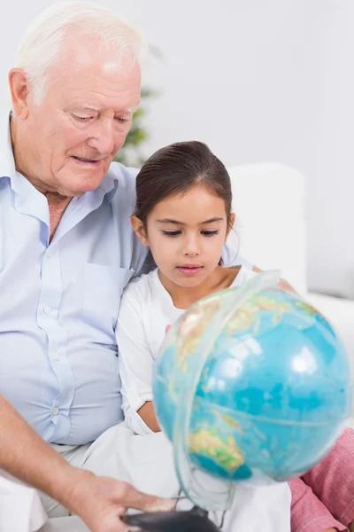 Souriant petite-fille et grand-père avec globe — Photo