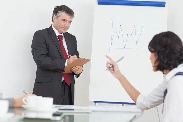 Businessman writing on clipboard in office — Stock Photo, Image