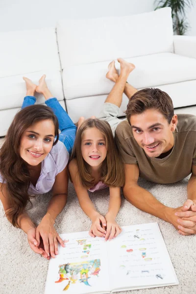 Familie mit einem Buch, das auf einem Teppich liegt — Stockfoto