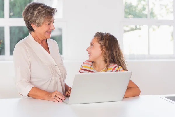 微笑的孩子和奶奶凝视着用的笔记本电脑 — 图库照片