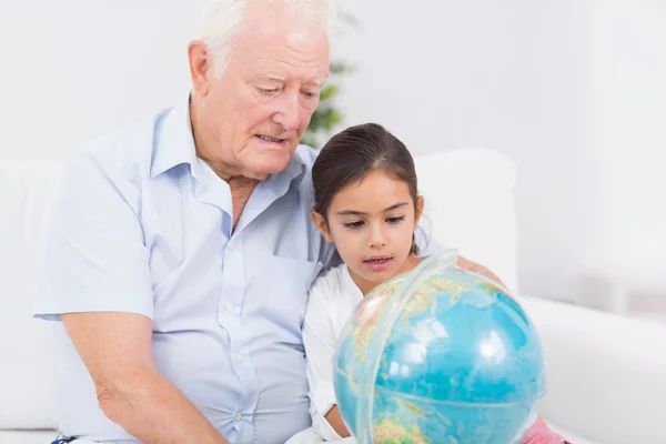 Petite-fille et grand-père avec globe — Photo