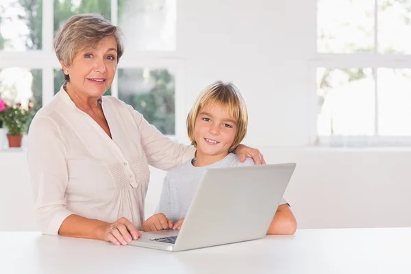 Oma und Kind suchen Kamera mit Laptop — Stockfoto