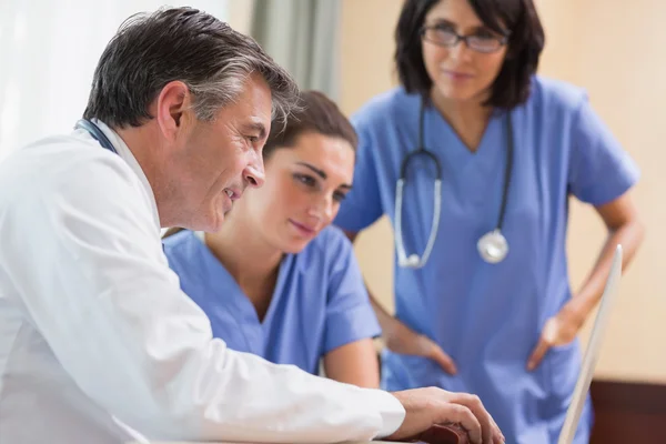 Médico y dos enfermeras mirando el portátil —  Fotos de Stock