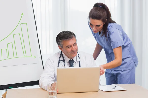 Arzt zeigt Krankenschwester etwas auf Laptop — Stockfoto