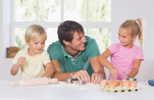 Father and his children cutting cookies out — Stock Photo, Image