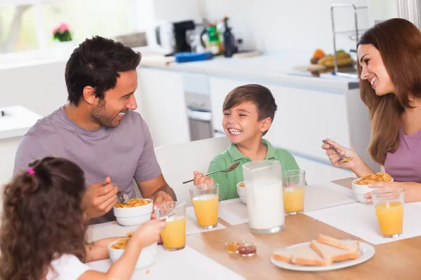 Familjen skrattar runt frukost — Stockfoto