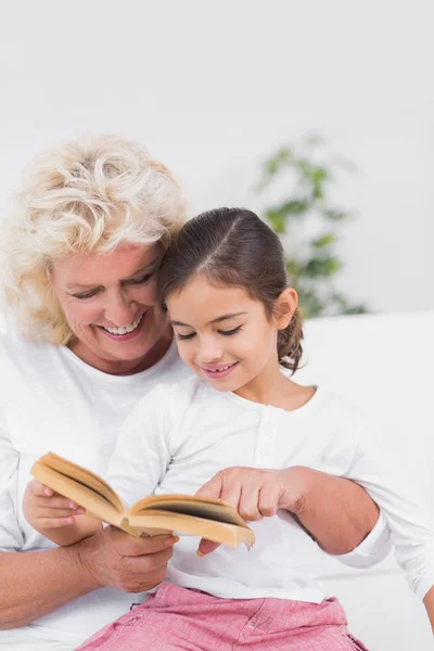 Cheerful granddaughter and grandmother reading a novel together — Stock Photo, Image