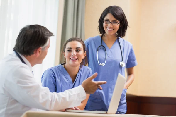 Lekarz uśmiechający się pielęgniarki wyświetlone coś na laptopie — Zdjęcie stockowe