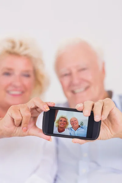 Aged couple taking pictures with smartphone — Stockfoto