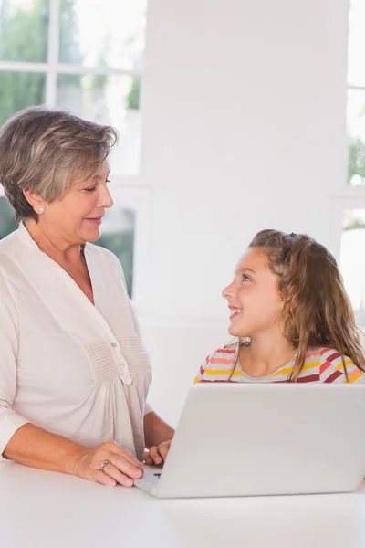 Souriant grand-mère et enfant regardant avec ordinateur portable — Photo