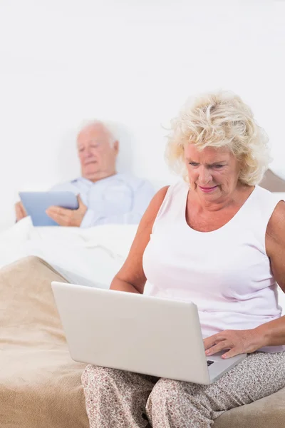 Пожилая пара с помощью планшета и ноутбука — стоковое фото