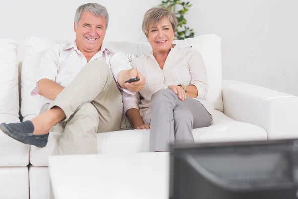 Vieux couple regardant la télévision avec les jambes croisées — Photo