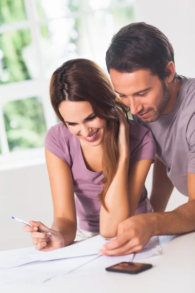 Smiling couple in front of invoices — Stock Photo, Image