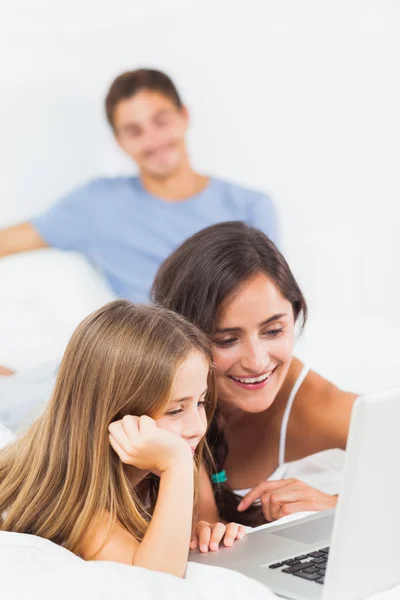 Familia feliz sentado con un ordenador portátil — Foto de Stock