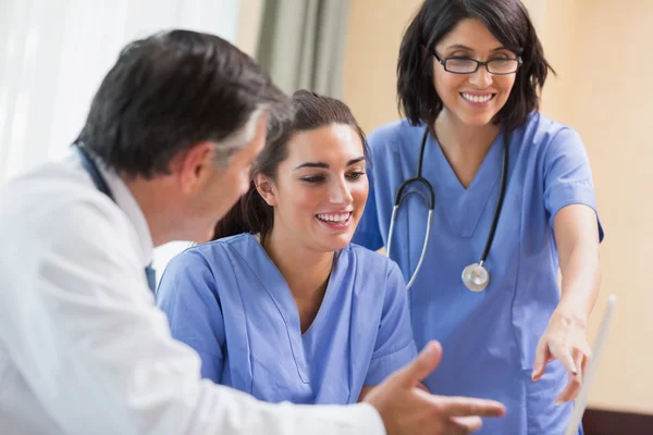 Médico y enfermeras mirando el portátil — Foto de Stock