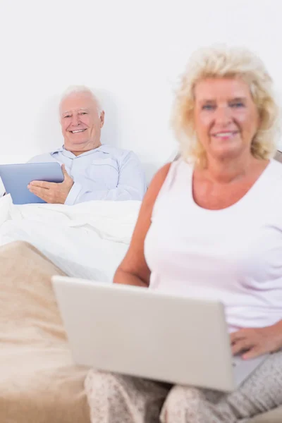 Feliz pareja de edad utilizando una tableta y el ordenador portátil — Foto de Stock