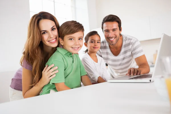 Familia feliz mirando a la cámara con un portátil — Foto de Stock