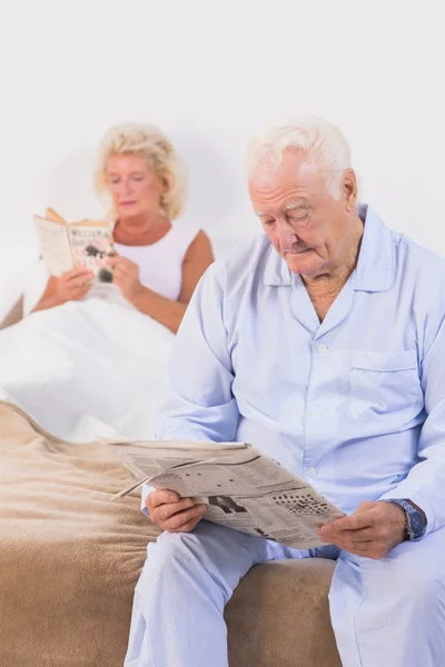 Pareja anciana leyendo en la cama — Foto de Stock