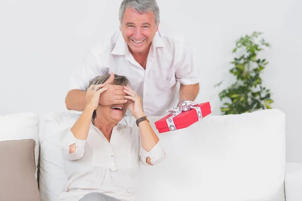 Old man hiding eyes of his wife for a gift — Stock Photo, Image