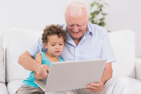 Grootvader en kleinzoon kijken naar een laptop scherm — Stockfoto