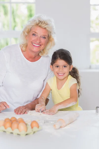 Petite-fille et grand-mère préparant ensemble des biscuits — Photo