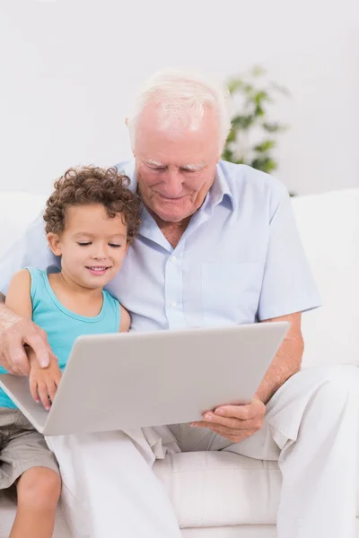 Grootvader en kleinzoon kijken naar een laptop — Stockfoto