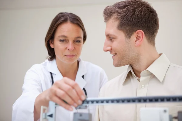 Doctor adjusting scale for her patient — Stock Photo, Image