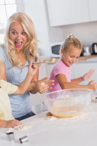 Mère faisant une grimace pendant que ses enfants prennent soin de la pâte — Photo