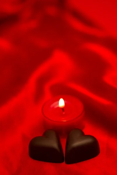 Chocolate hearts and lit candle — Stock Photo, Image