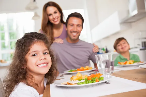 Familia sonriendo a la cámara en la mesa de la cena — Foto de Stock