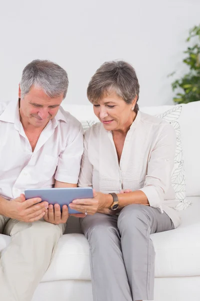 Altes Ehepaar schaut lächelnd auf Tablet-PC — Stockfoto